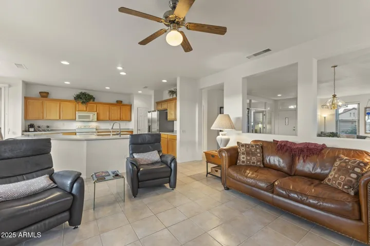 Bright and inviting family room featuring tile flooring, ceiling fan, and open connection to the kitchen—perfect for entertaining and everyday comfort.