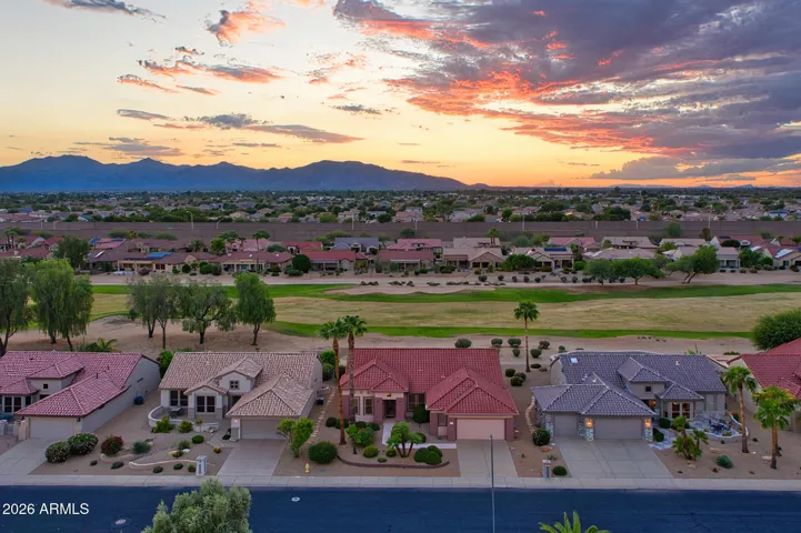 Stunning golf course property in Surprise featuring panoramic fairway views framed by distant mountains. The landscaped yard and Spanish-style roof create a warm, inviting curb appeal that perfectly captures Arizona living.