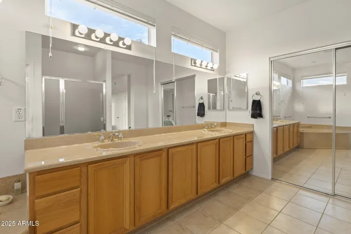 Elegant primary bath with dual sinks, full wall mirror, and abundant storage—featuring natural light and modern fixtures for a polished finish.