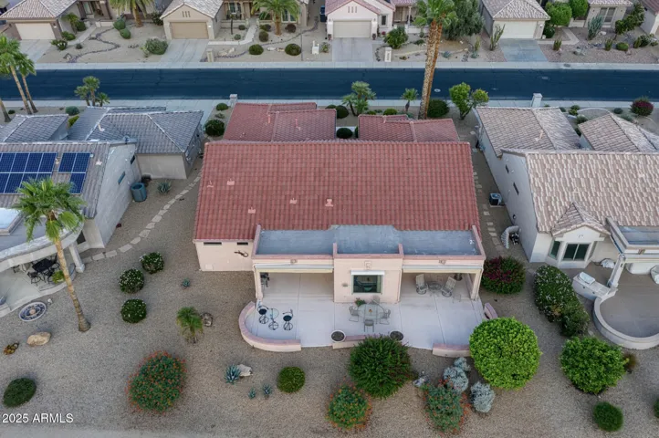 Aerial rear view reveals the spacious covered patio and outdoor seating area designed for entertaining or relaxing while soaking in sweeping fairway views in this beautifully maintained Surprise home.