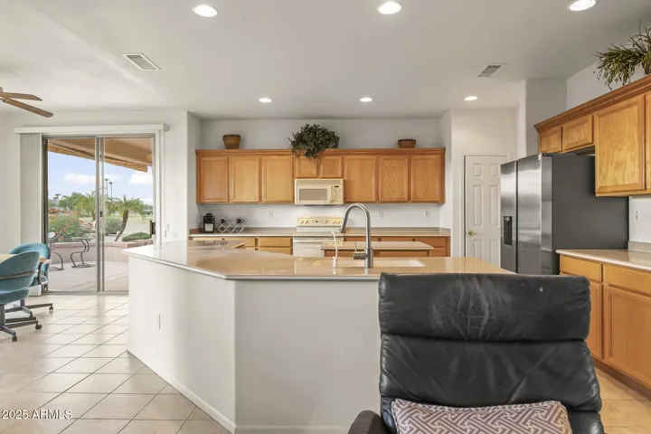 Modern kitchen featuring a large center island, ample storage, stainless refrigerator, and upgraded lighting—ideal for cooking and entertaining.