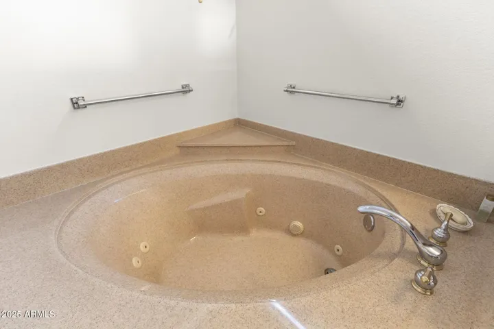 Luxurious corner jetted tub surrounded by solid-surface finishes, ideal for unwinding in comfort within this bright and airy main bathroom.