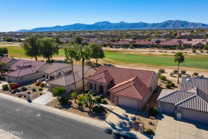 Charming home exterior with tile roof, colorful desert landscaping, and lush greenery that perfectly complements the sunny Arizona setting.