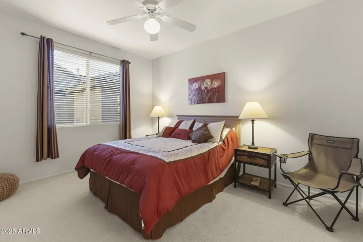 Inviting guest bedroom with plush carpet, neutral walls, and warm natural light, creating a peaceful space for visiting friends or family.