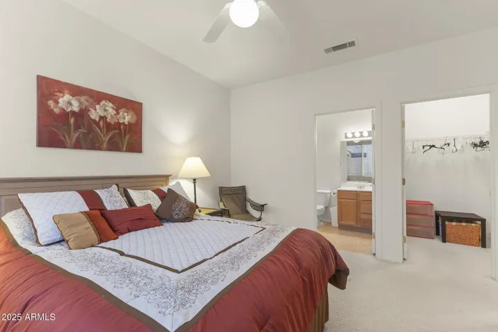 Bright guest room with ceiling fan, ensuite access to a private bath, and walk-in closet—offering both privacy and convenience.