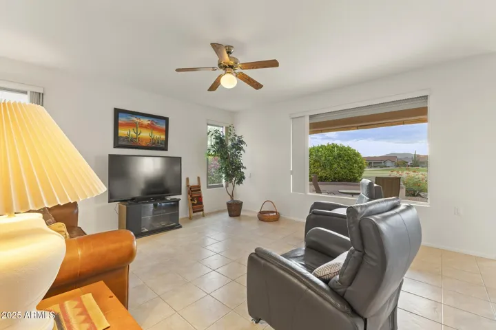 Expansive family room with picture window overlooking the lush golf course, offering peaceful views and a relaxing retreat in this Surprise residence.