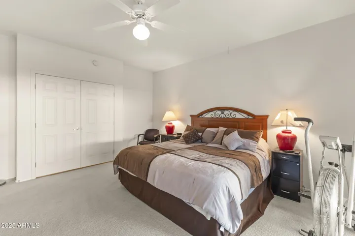 Bright primary bedroom featuring neutral tones, ceiling fan, and private patio access, designed for comfort and tranquility.