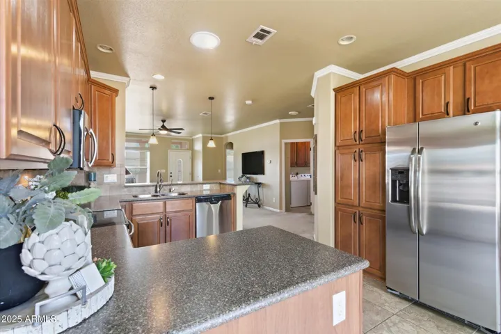 Gorgeous open kitchen with quartz countertops, tile backsplash, and upgraded maple cabinetry offering abundant storage.