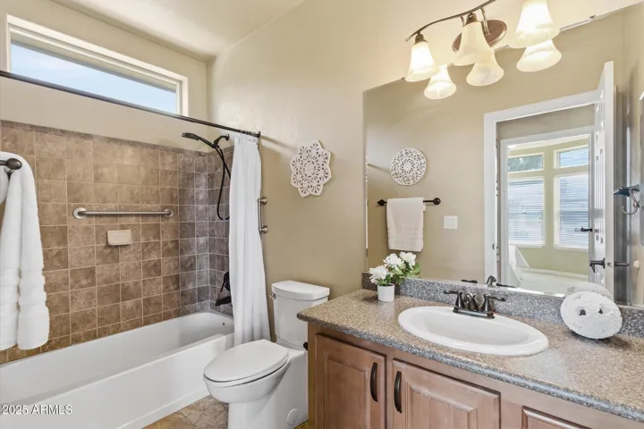 Upgraded guest bath includes a tub and shower with travertine tile surround walls, updated shower assembly, updated vanity with Quartz counter tops, sink, faucet and light fixture,