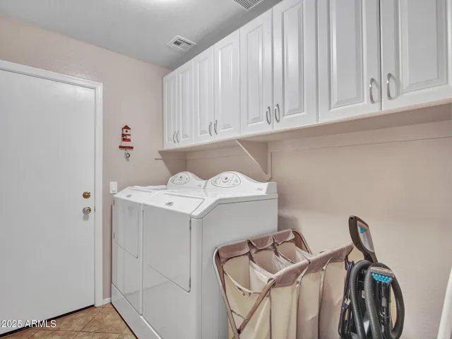 Dedicated laundry room with overhead cabinetry, washer and dryer space, and tile flooring for added convenience and organization.