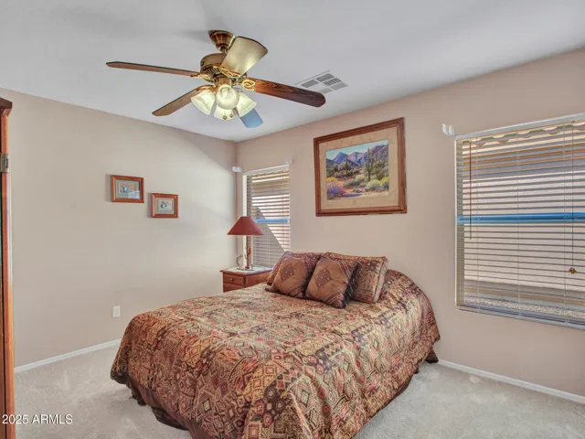 Comfortable bedroom featuring plush carpet, ceiling fan, and neutral tones, creating a relaxing space ideal for guests or everyday living.