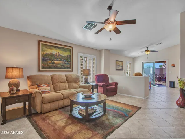 Spacious living room with tile flooring, ceiling fan, and open layout connecting to dining and kitchen areas. Designed for comfort and entertaining in Buckeye.