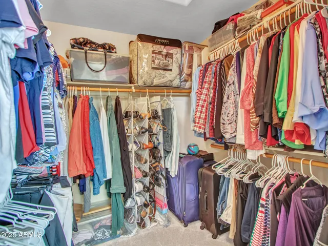 Large walk-in closet featuring built-in shelving, hanging rods, and organized storage space to accommodate clothing, shoes, and luggage.