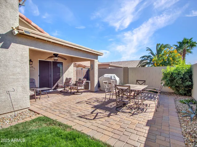 Private backyard enclosed by block fencing, with lawn and paver patio areas designed for comfort and functionality.