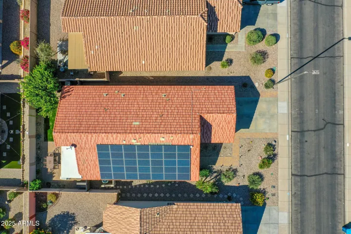This top-down aerial view clearly displays the home’s solar panel system and roof layout, offering a strong visual of its energy-efficient features. The surrounding yards, walkways, and street placement are visible, providing buyers with a clear sense of the property’s footprint and neighborhood setting in Buckeye.