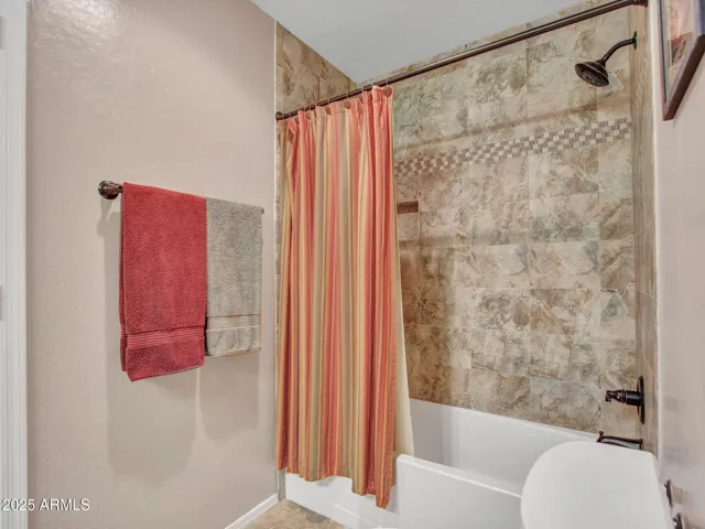 Bedroom featuring carpet flooring, ceiling fan, and convenient access to an en-suite bathroom for added privacy and comfort.