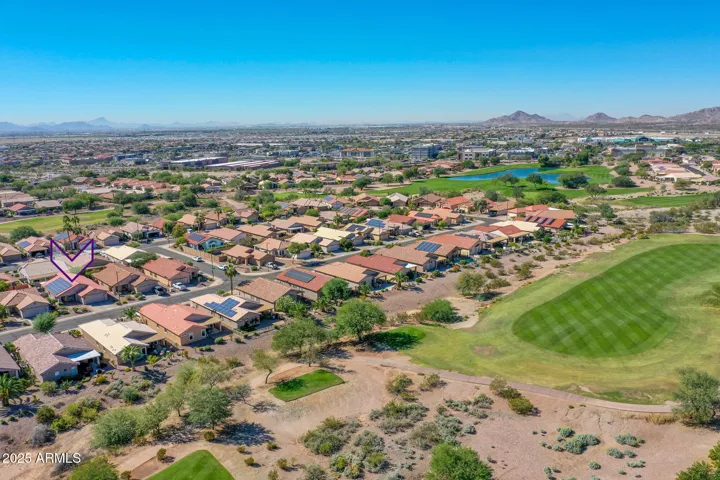Aerial view highlights the home’s location near green golf course fairways and surrounding Buckeye neighborhood with desert landscaping.
