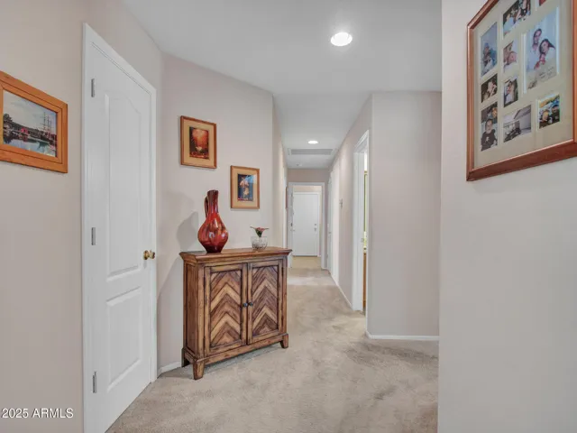 Carpeted interior hallway featuring recessed lighting and nearby storage, offering a clean, functional transition between bedrooms and living spaces.