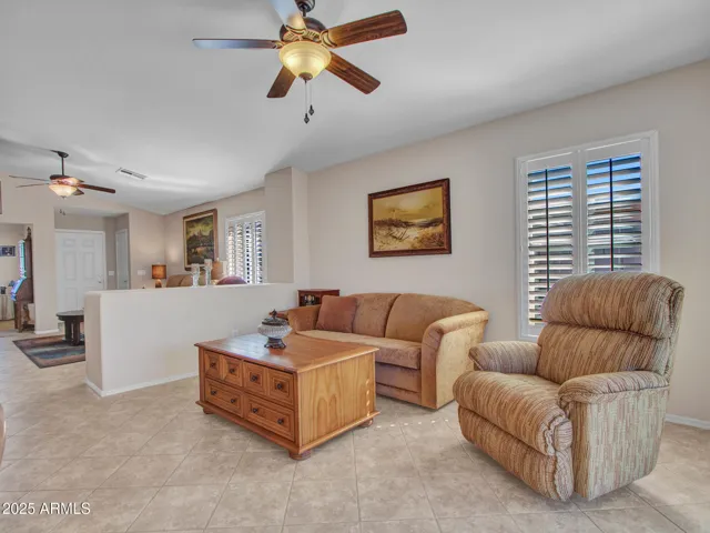Spacious family room with neutral tones, tile floors, and ceiling fan. The open layout connects seamlessly to dining and kitchen areas for easy entertaining.