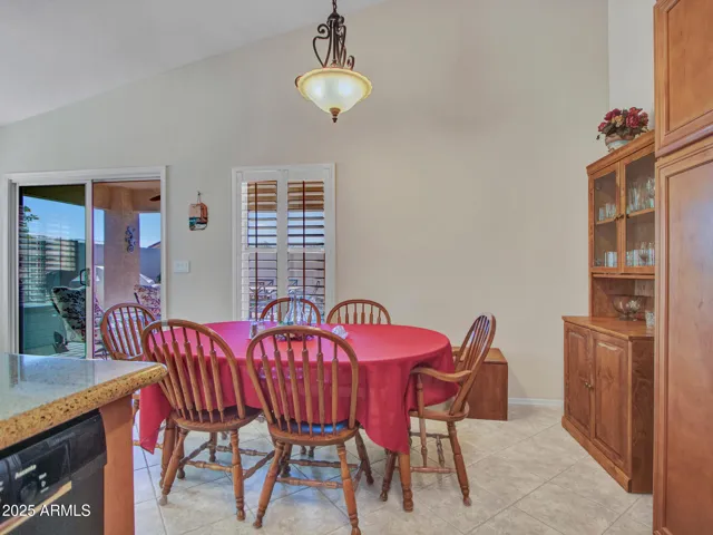 Dining area positioned near sliding glass doors and kitchen, allowing natural light and easy access to outdoor entertaining spaces.