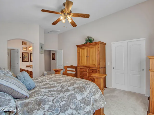 Spacious primary bedroom featuring vaulted ceilings, ceiling fan, plush carpet, and neutral tones. Designed for comfort and relaxation in this Buckeye home.