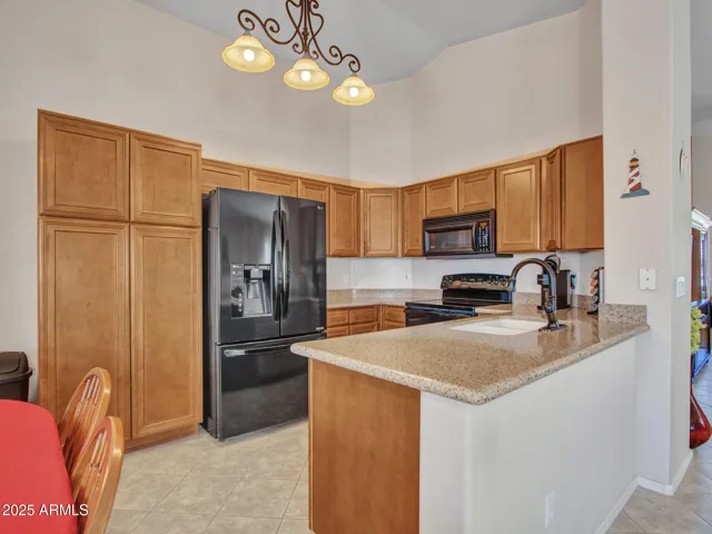 Well-appointed kitchen featuring granite countertops, warm wood cabinetry, black appliances, and a breakfast bar for casual seating.