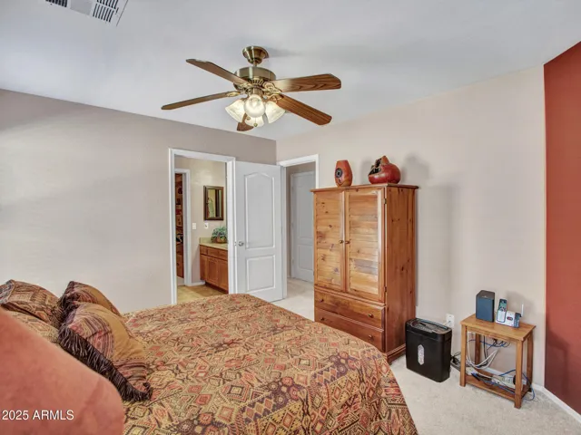 Bright bedroom with large window, soft carpet, and ceiling fan, offering a peaceful retreat filled with natural light.