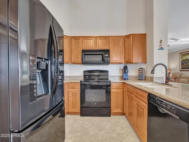 Functional kitchen equipped with black appliances, granite countertops, and generous cabinet space. Designed for efficiency and everyday use.