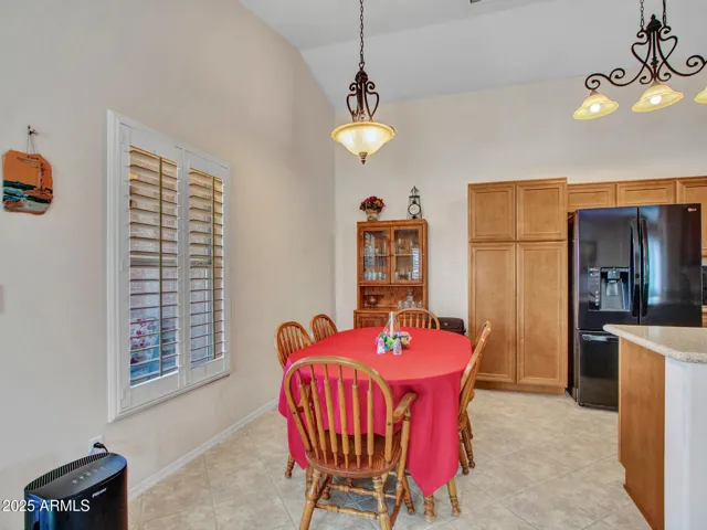 Bright dining area featuring vaulted ceilings, tile flooring, and space for a full dining set. Conveniently located off the kitchen.
