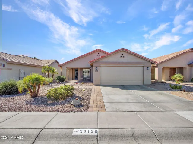 Wide driveway leading to a two-car garage, offering ample parking and everyday convenience. The front elevation highlights the home’s well-kept exterior in a quiet Buckeye neighborhood.