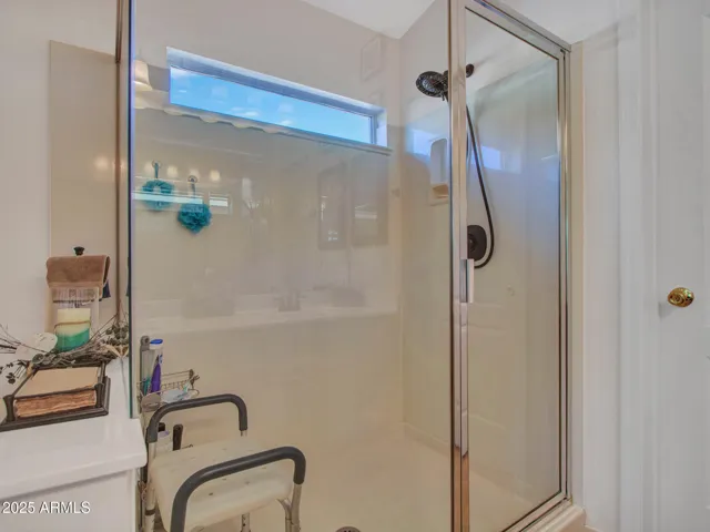 Walk-in shower with glass enclosure, built-in ledge, and natural light creates a clean, easy-access bathing space.