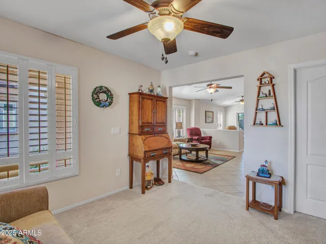 Quiet office or den featuring carpeted flooring, ceiling fan, and natural light. A functional space that adapts to work-from-home or guest needs.