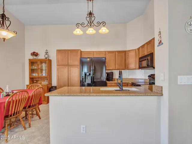 Kitchen highlights include granite countertops, raised breakfast bar, pendant lighting, and ample cabinetry for storage and functionality.