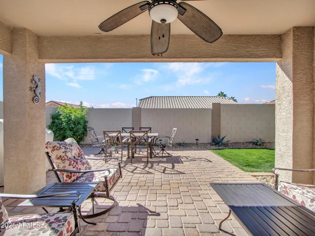 Covered backyard patio featuring paver flooring and ceiling fan, creating a shaded outdoor living space ideal for relaxing or entertaining in Buckeye.