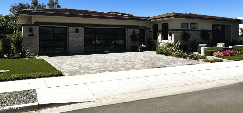 Front of home with 3 car garage and upgraded Cloplay Etched Glass Modern Garage Doors. Garage has an epoxy finish & 2 Tankless Hot Water Tanks and service door.