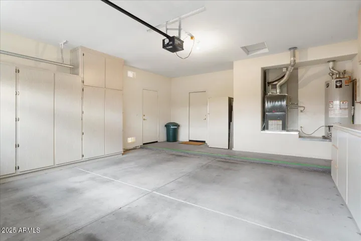 The garage has nice cabinets for storage, and a door to the side of the house. The doorway at the top of the photo is the direct entrance into the laundry room area of the house.