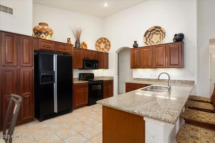 The kitchen has black appliances and even has a pantry wall to the left of the refrigerator! Nice storage space!