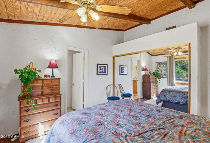 Primary suite with mirrored closet doors and wood ceilings. Bright and inviting space in Hackberry AZ desert home.