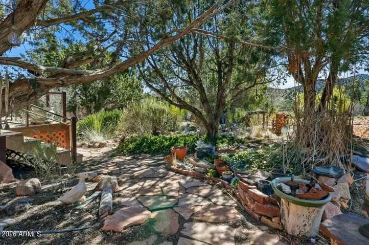 Natural stone walkway through mature trees and garden beds creating a tranquil landscape setting in Hackberry Arizona.