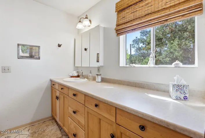 Bright bathroom vanity with window views and cabinet storage. Comfortable everyday living in Hackberry Arizona.