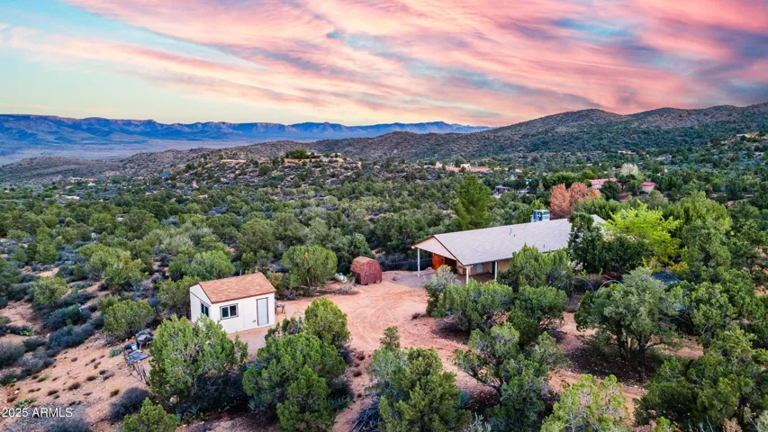 Overlooking the property, this image captures the home nestled among lush desert vegetation with stunning mountain ridgelines beyond. Designed for peaceful living, the setting offers privacy, natural beauty, and breathtaking Hackberry horizons.