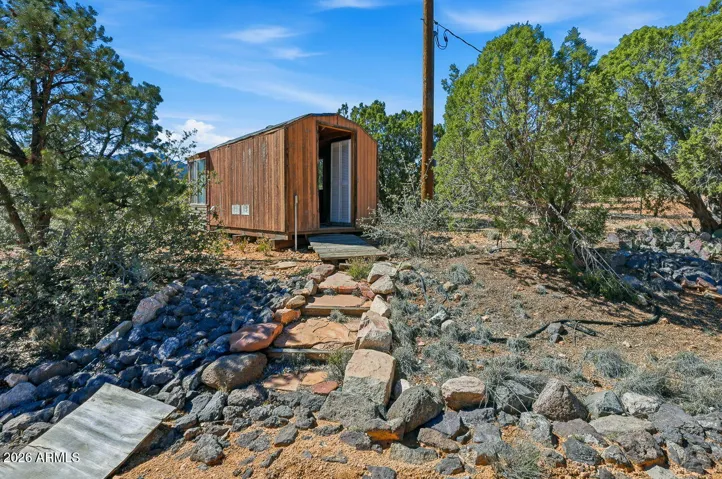 Detached rustic shed with stone pathway access. Ideal for storage, workshop or creative space in Hackberry Arizona.
