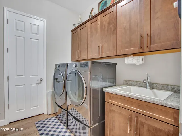 A functional, stylish laundry featuring rich cabinetry, utility sink, and additional linen closet.