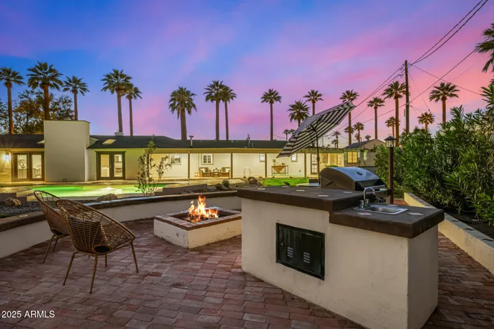The red brick BBQ Terrace is set at the rear of the yard just steps from the pool and an expanse of grass. Enjoy weekend cookouts and conversations around the firepit in a garden setting.