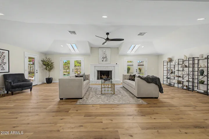 The great room features a gorgeous fireplace, french doors on either side of the marble clad fireplace, and there is plenty of room for conversation nooks, book cases, and more.