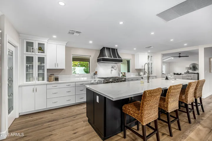 The kitchen has been redesigned to include glass-front cabinetry and picture windows to the back yard and pool.