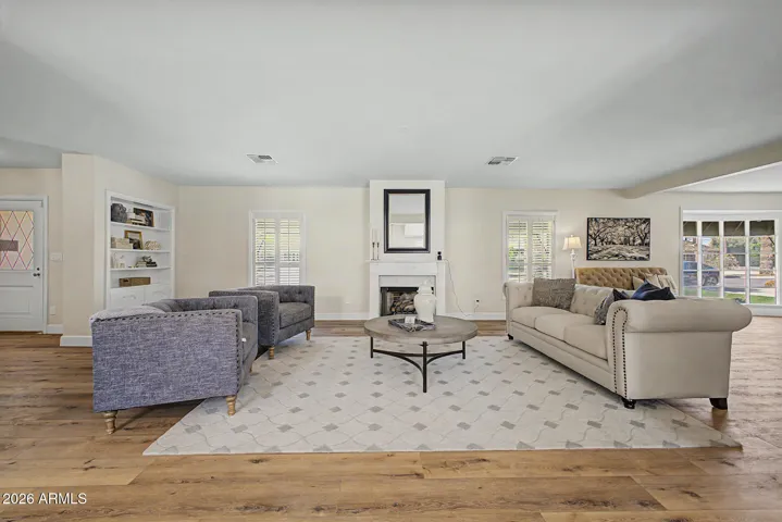 The sitting room exempifies the symmetry of Colonial Revivalism with large windows that flank the central fireplace.