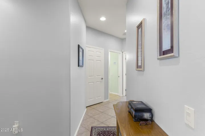Hallway just outside primary suite leading to the guest area and laundry/garage.