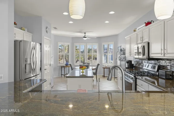 Kitchen from breakfast bar showing granite tops, island, pantry, appliances, breakfast nook