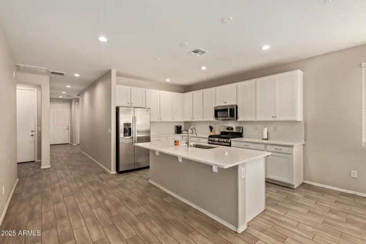 Stylish kitchen featuring oversized island, white cabinetry, subway tile backsplash, and stainless steel appliances. Functional design with ample prep space and storage.
